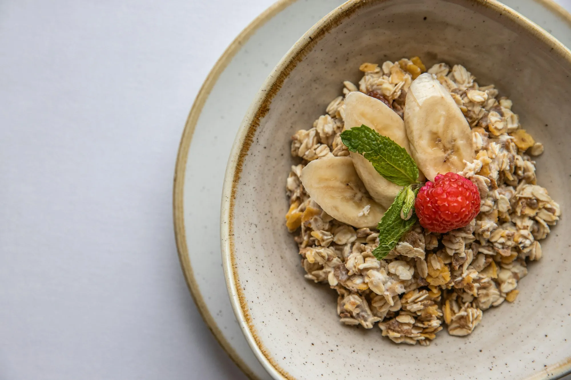 Tigela de aveia com banana fatiada, morango e folha de hortelã
