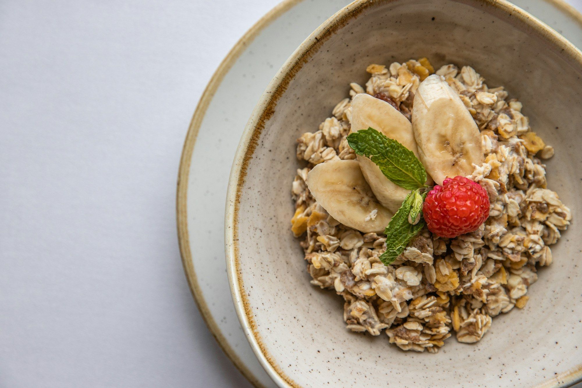 Tigela de aveia com banana fatiada, morango e folha de hortelã